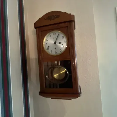 Vintage Linden wall clock with a wooden case, brass pendulum, and glass window display.