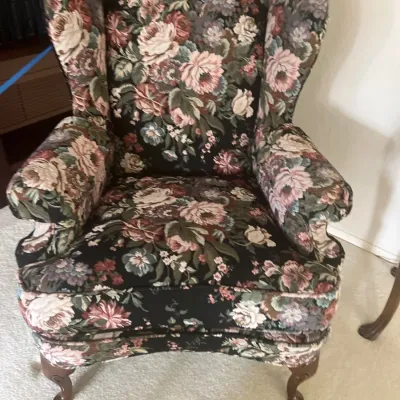 Traditional wingback armchair upholstered in a dark floral tapestry fabric, supported by wooden cabriole legs.