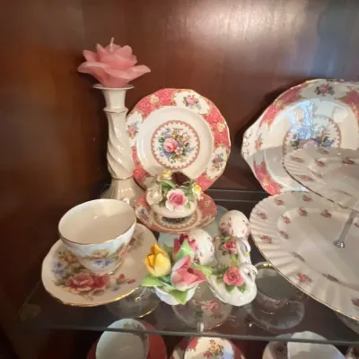 Collection of vintage porcelain floral tableware and figurines, including teacups, saucers, decorative plates, and a candle holder.