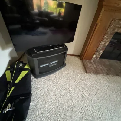 Large Sony flat-screen television resting on a dark gray media cabinet next to a black and neon yellow sports bag.