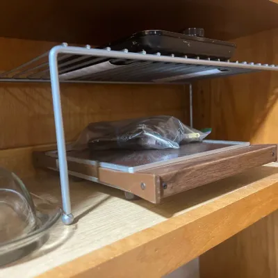 Vintage electric warming tray with wood trim, stored in a cabinet under a wire shelf organizer.