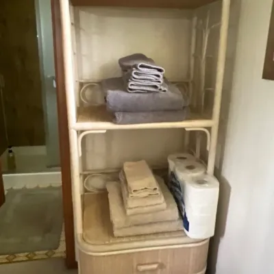 Vintage white rattan and wicker bathroom etagere featuring three display shelves and two bottom drawers.