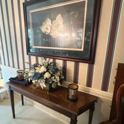 Traditional wooden sofa console table with tapered legs, topped with artificial floral arrangements and decorative glass candle holders,...