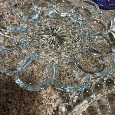 Clear press glass deviled egg platter featuring a starburst center design and scalloped edge, in good condition.