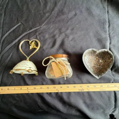 Collection of decorative trinkets including a heart-shaped caduceus music box, a small glass potpourri jar, and an iridescent mosaic...