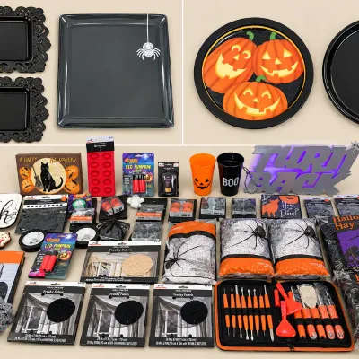 Large collection of Halloween party supplies and decorations, including serving trays, spiderweb webbing, pumpkin carving tools, themed...