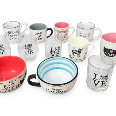 Collection of modern cat-themed ceramic mugs, glassware, and soup bowls featuring various slogans and illustrations.