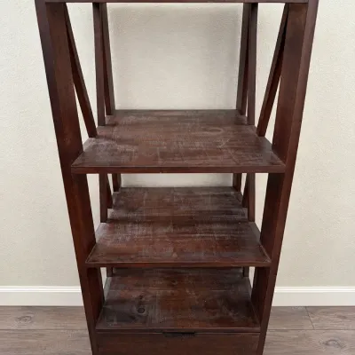 Dark stained wooden three-tier bookshelf featuring a bottom drawer and open, angled side bracing. Shows light surface wear and scratching...