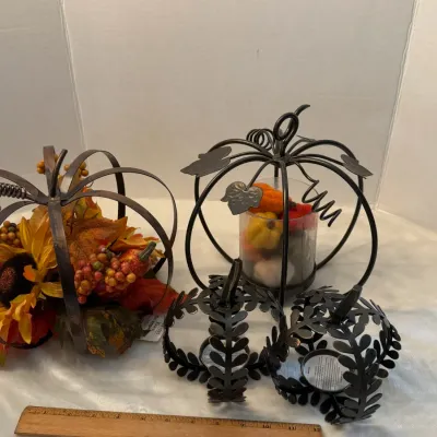Collection of autumn and harvest-themed metal wire pumpkin decorations, including candle holders and artificial floral arrangements.