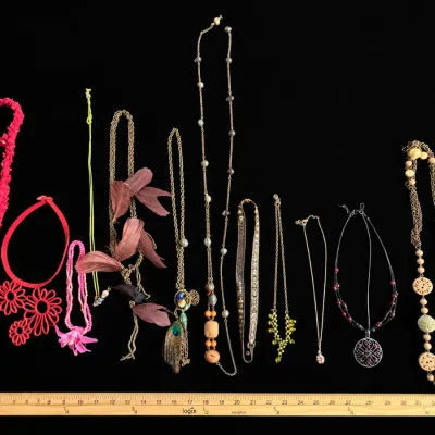 Eclectic assortment of vintage and modern fashion necklaces, including beaded, feather, fabric, and pendant styles, shown alongside...
