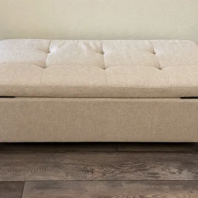Contemporary tufted beige upholstered storage ottoman bench with black tapered wooden legs.