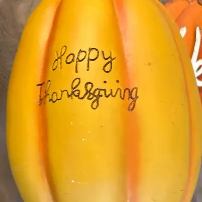 Decorative yellow and orange resin pumpkin featuring script lettering that reads 'Happy Thanksgiving'.