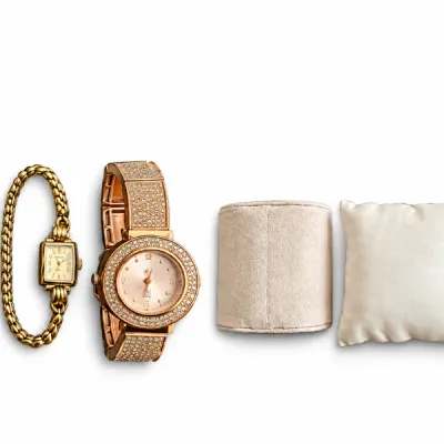 Collection of four women's fashion watches alongside display cushions and a heart-shaped metal trinket box with a palmetto tree motif.