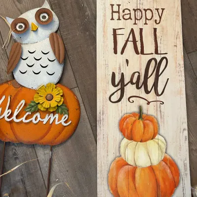 Autumn decorative items, including a metal owl garden stake with a pumpkin base and a faux-wood rustic sign reading 'Happy Fall...