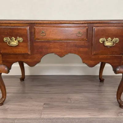 Queen Anne style mahogany lowboy featuring cabriole legs, a shaped apron, and original brass bail handles.