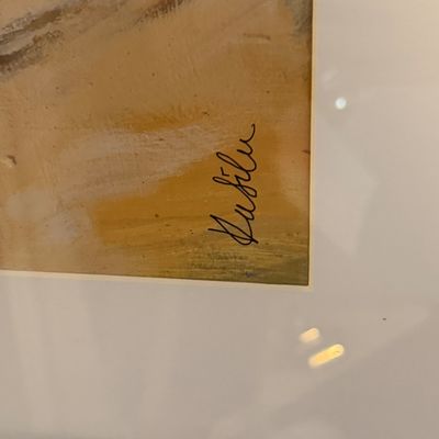 Close-up detail of an artist's cursive signature on the corner of a framed artwork.