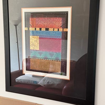 Framed contemporary abstract artwork featuring colorful geometric patterns and metallic gold foil accents, presented in a black frame...