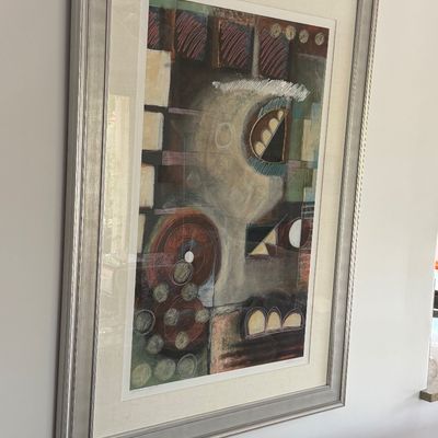 Large framed abstract artwork featuring geometric shapes and muted tones, presented in a silver-finish molded frame.