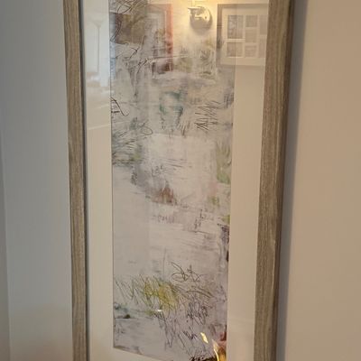Large contemporary abstract art print featuring scribbled line details and muted tones, presented in a light wood frame behind glass.