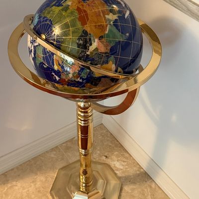 Gemstone ocean floor globe set in lapis blue with semi-precious stone continents, mounted on a polished brass floor stand.