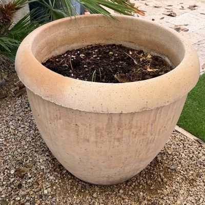 Large terracotta-colored composite outdoor planter filled with soil, showing light weathering consistent with garden use.