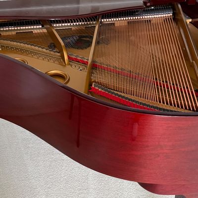 Polished mahogany baby grand piano, open view showing clean internal soundboard, strings, and cast-iron frame in excellent condition.