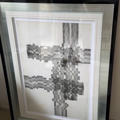 Framed black and white abstract print featuring geometric crosshatch patterns, housed in a wide silver-toned metallic and black accent...