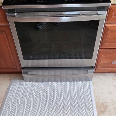 Modern GE stainless steel slide-in electric range with a glass flat cooktop and front-facing digital control panel.