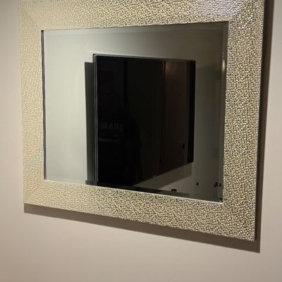 Contemporary wall mirror featuring a broad rectangular frame composed of silver mosaic tiles.