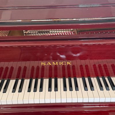 Samick baby grand piano featuring a polished mahogany finish and clean keys.