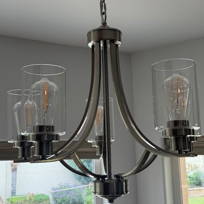 Modern five-light chandelier in a brushed nickel finish with cylindrical clear glass shades and filament bulbs.