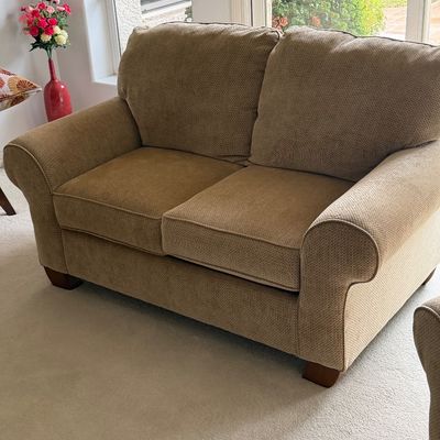 Contemporary tan textured fabric loveseat featuring rolled arms and wooden feet in good condition.