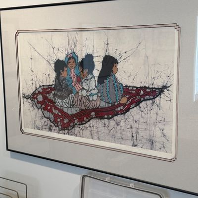 Framed batik textile art print depicting Indigenous children seated on a woven rug, double-matted in a slim black frame.