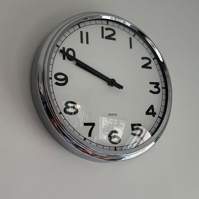 Round wall clock with a chrome frame, white face, and bold black numerals.