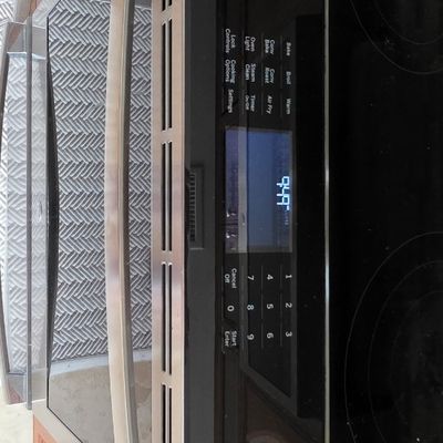 Modern stainless steel and black glass slide-in electric range with a digital control panel.