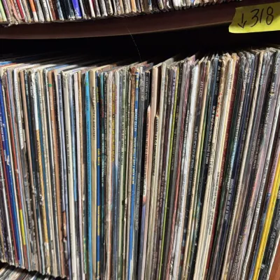 Sale Photo Thumbnail #112: Large collection of vintage 33 RPM vinyl records stacked vertically on a wooden shelf.
