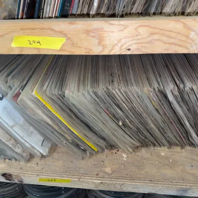 Sale Photo Thumbnail #84: Large shelf of vintage vinyl records in protective plastic sleeves, shown stored upright.