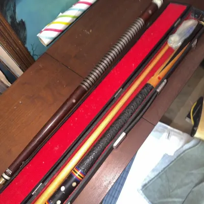 Sale Photo Thumbnail #183: Vintage two-piece pool cue set featuring colorful inlay details and a textured wrap, resting inside a red felt-lined hard carrying case.
