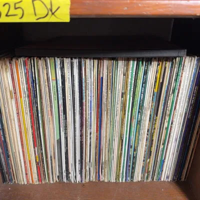 Sale Photo Thumbnail #128: Large collection of vintage vinyl LP records neatly arranged vertically inside a wooden shelf.