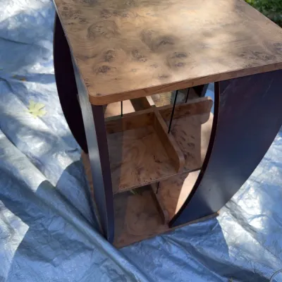 Sale Photo Thumbnail #37: Vintage burl wood veneer rotating record rack side table featuring curved dark wood sides and divided storage compartments.
