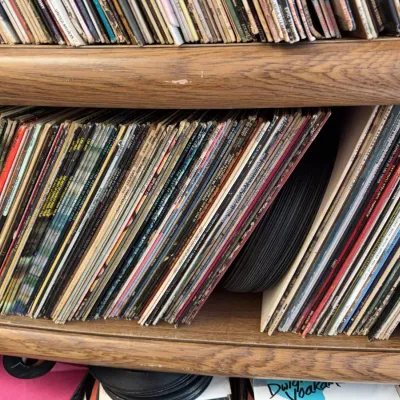 Sale Photo Thumbnail #101: Large collection of vintage vinyl LP records stacked on wooden bookshelf shelves.