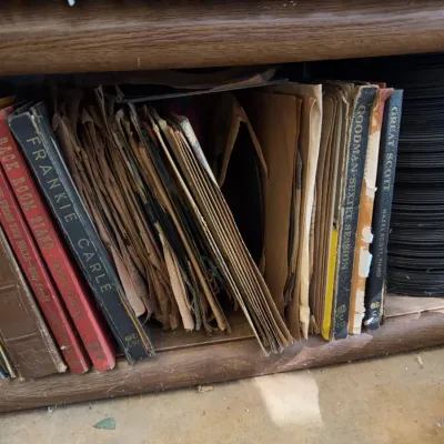 Sale Photo Thumbnail #104: Collection of vintage 78 RPM record albums and loose shellac discs stored on a wooden shelf, including titles by Frankie Carle, Benny Goodman, and Hazel Scott.