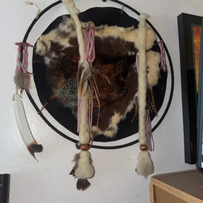 Sale Photo Thumbnail #190: Native American-style decorative wall shield featuring fur, feathers, beadwork, and fur-wrapped wooden struts mounted on a circular frame.