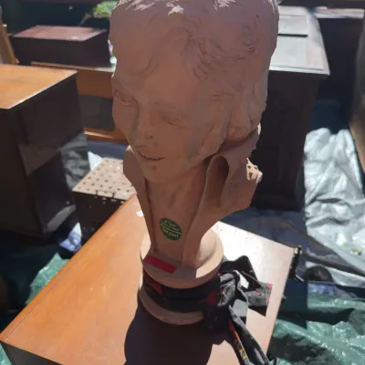Sale Photo Thumbnail #74: Terracotta or plaster portrait bust sculpture of a man, likely Elvis Presley, mounted on a round pedestal base.
