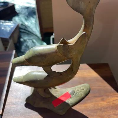 Sale Photo Thumbnail #52: Vintage brass figurine depicting two swimming dolphins on an organic-shaped base, featuring an aged patina.