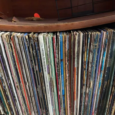 Sale Photo Thumbnail #115: Collection of vintage 33 RPM vinyl LP records, stacked closely on a wooden shelf.