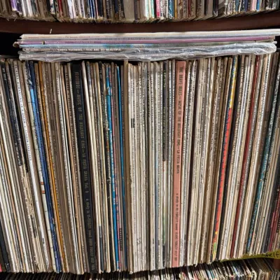 Sale Photo Thumbnail #116: Large collection of vintage 33 RPM vinyl LP records organized on a wooden shelf, featuring various music genres and artists.