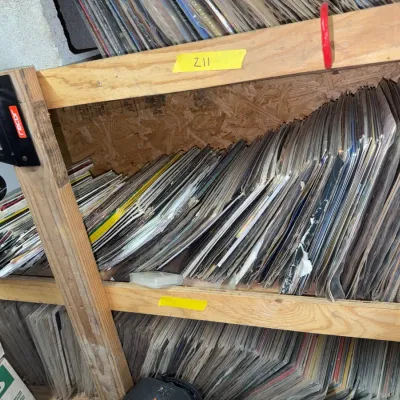 Sale Photo Thumbnail #92: Large collection of vintage vinyl LP records stacked on wooden shelving.