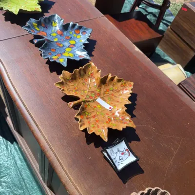 Sale Photo Thumbnail #62: Collection of mid-century glazed ceramic leaf-shaped dishes displayed on a wooden furniture piece.