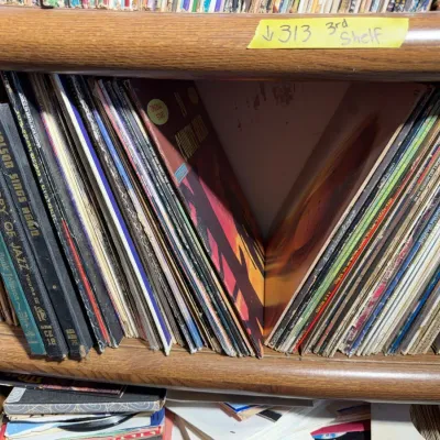 Sale Photo Thumbnail #107: A collection of vintage vinyl LP records and record sets organized on a wooden shelf, including titles on jazz and country music.